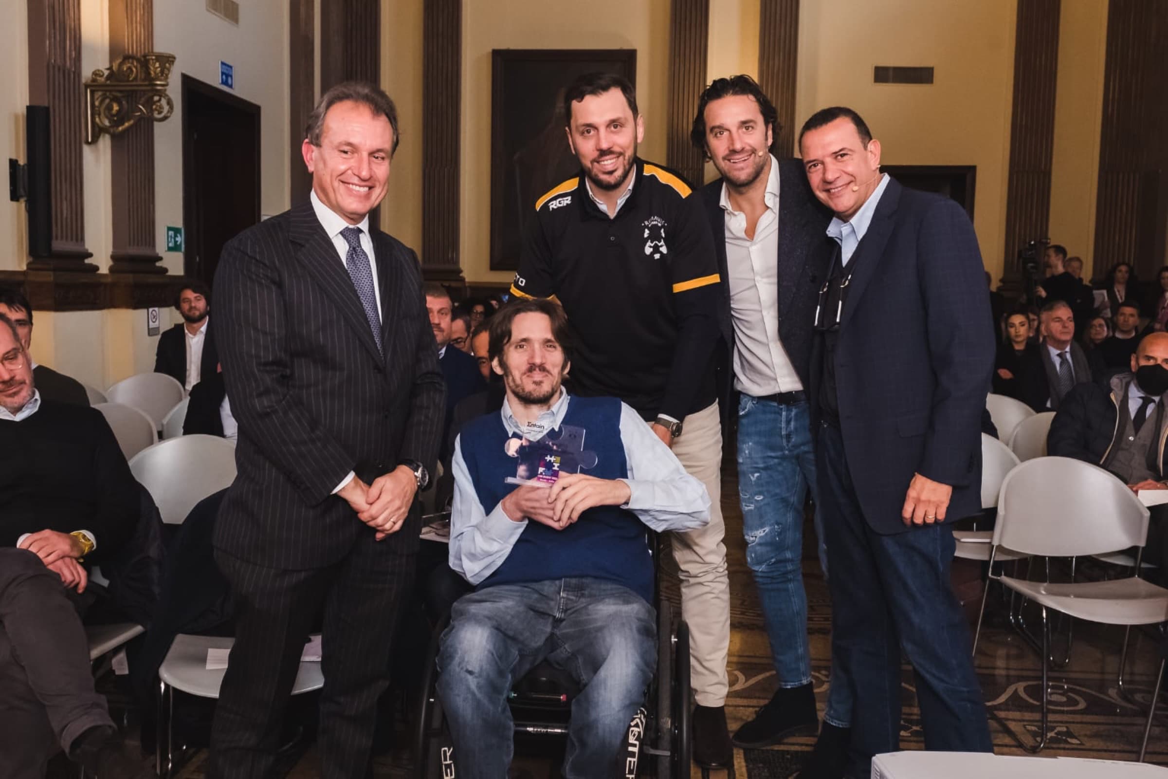 Rufo Iannelli e lo staff dei Romanes sul palco con il riconoscimento del Premio Entain per lo sport inclusivo.
